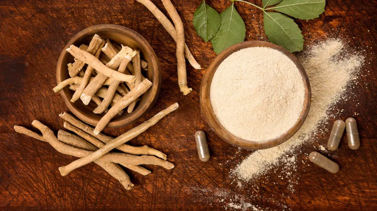 Ashwagandha-Wurzeln, Pulver und Kapseln auf Holzuntergrund. Ideal für eine entspannte Nachtruhe.