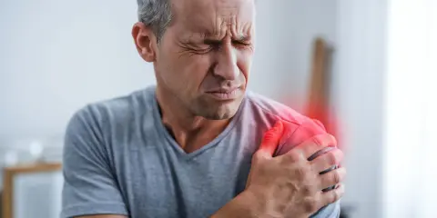 Mann mit schmerzender Schulter, die auf ein Impingement-Syndrom hindeutet, möglicherweise verschlimmert durch die Schlafposition.