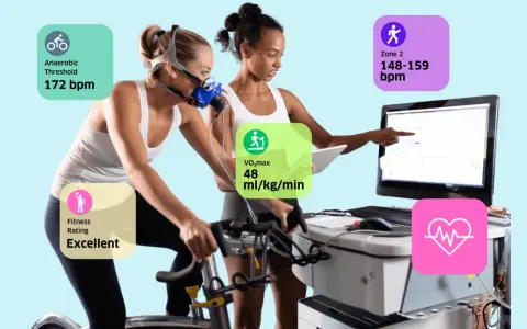 Frau auf Ergometer mit Maske, Trainer überwacht Werte wie VO2max (48 ml/kg/min), anaeroben Schwellenwert (172 bpm) und Fitness-Rating (Excellent).