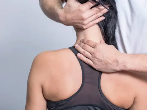 Hände eines Therapeuten untersuchen den Nacken einer Frau, um schmerzen seitlich am Hals entlang zu lindern.