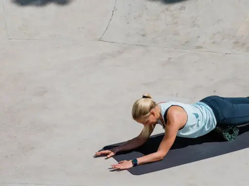 Frau rollt mit Foam Roller ihre Beine nach dem Laufen aus.