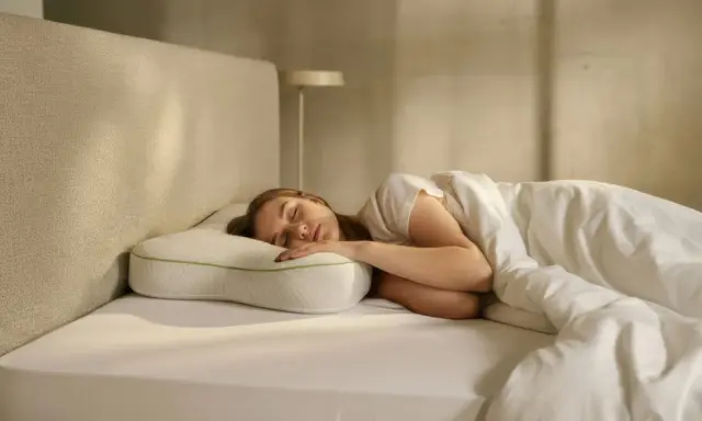 Junge Frau schläft tief und fest auf einem ergonomischen Kissen. Ein schnelles Hausmittel zum Einschlafen, das für erholsamen Schlaf sorgt.
