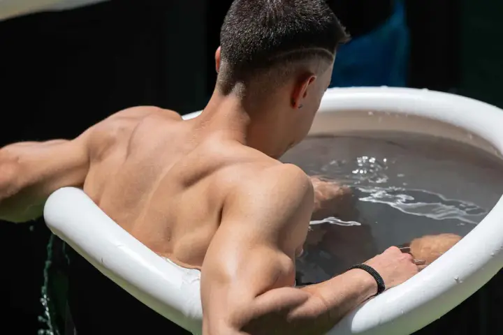 Mann sitzt im Eisbad, bereit für das warme Duschen danach.