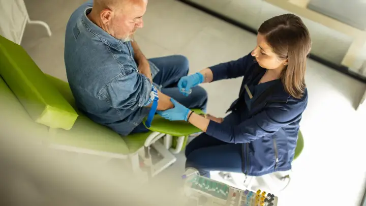 Arzt nimmt Blut ab, um das biologische Alter zu bestimmen. Die Ergebnisse werden in einer biologisches alter tabelle ausgewertet.